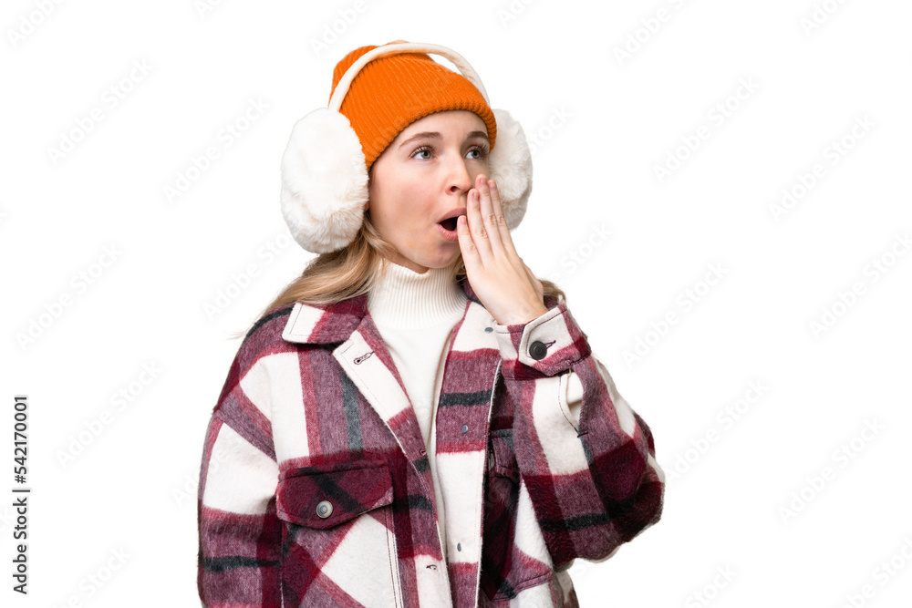 Young English woman wearing winter muffs over isolated background yawning and covering wide open mouth with hand Young English woman wearing winter muffs over isolated background yawning and covering wide open mouth with hand