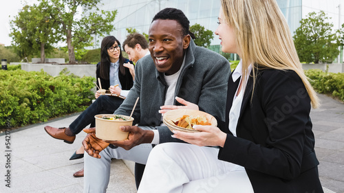Happy multiracial business people having a lunch break outside office photo