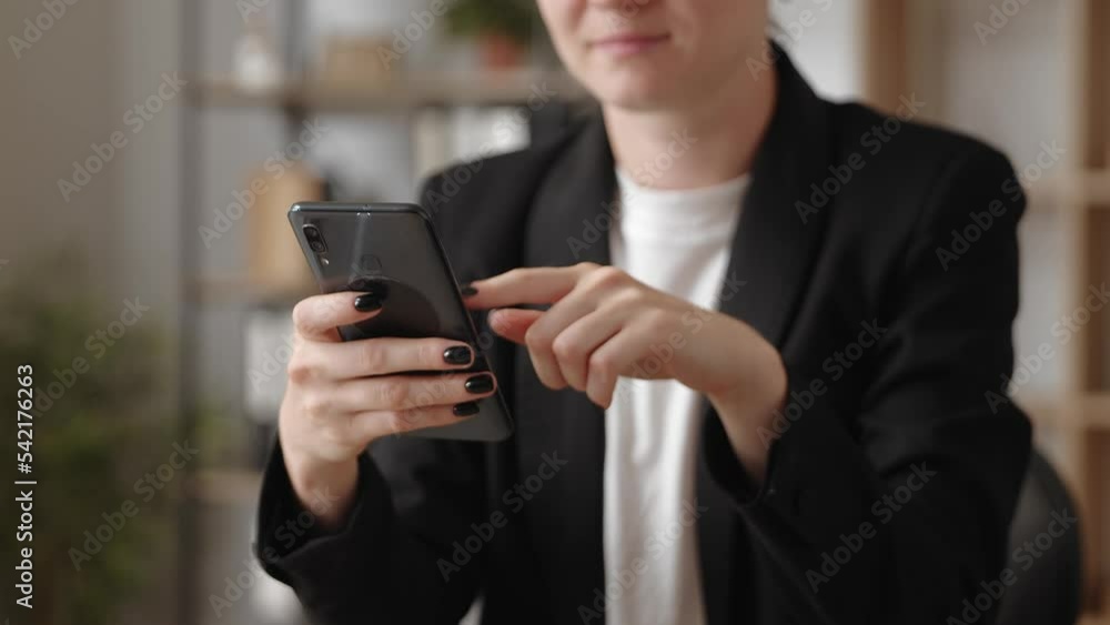 Female sitting at table holding smartphone, close up hands and device view. Female sitting at table holding smartphone, close up hands and device view.