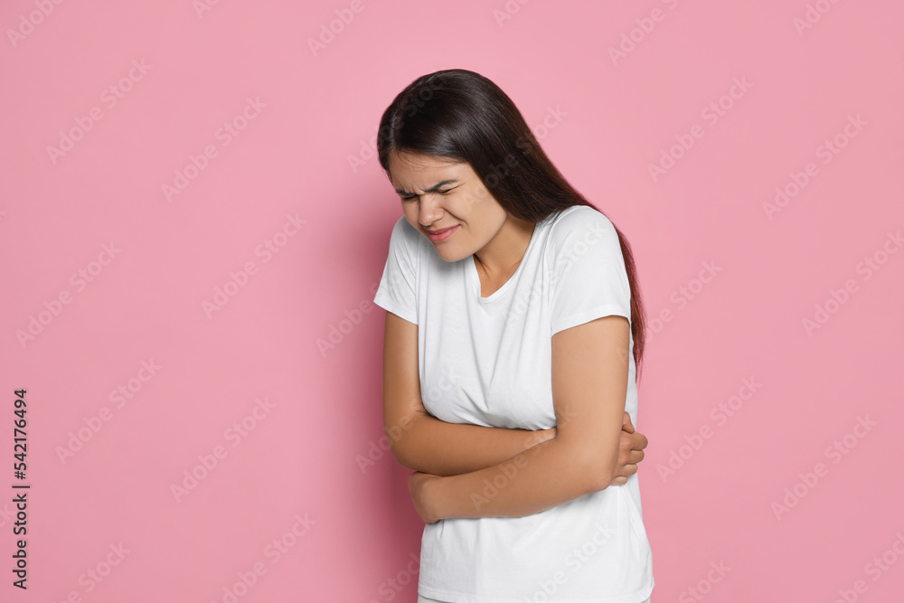 Young woman suffering from menstrual pain on pink background, space for text Young woman suffering from menstrual pain on pink background, space for text