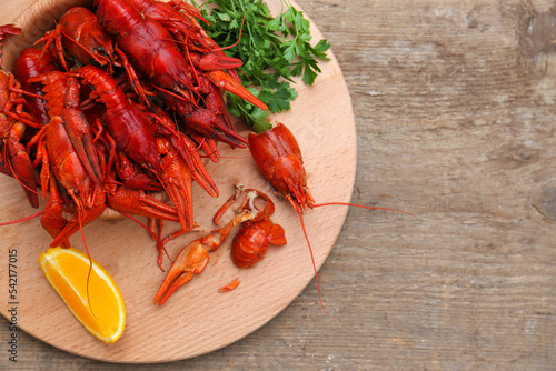 Delicious red boiled crayfish and orange on wooden table, top view