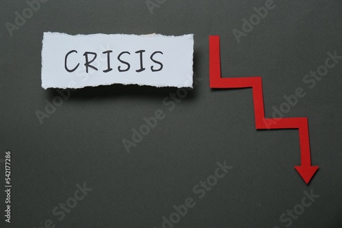 Canvas Print Paper piece with word Crisis and descending red arrow on black background, flat lay