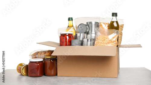 Donation box with food on light grey table against white background