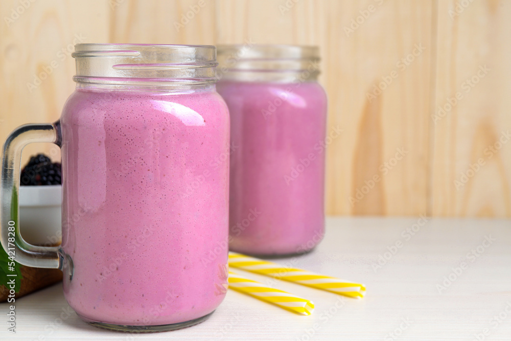 Mason jars of blackberry smoothie on white wooden table. Space for text Mason jars of blackberry smoothie on white wooden table. Space for text
