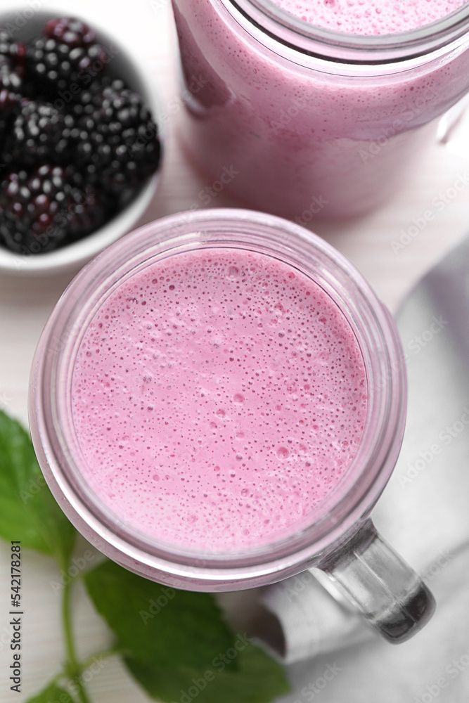 Mason jar of blackberry smoothie and berries on white table, flat lay Mason jar of blackberry smoothie and berries on white table, flat lay