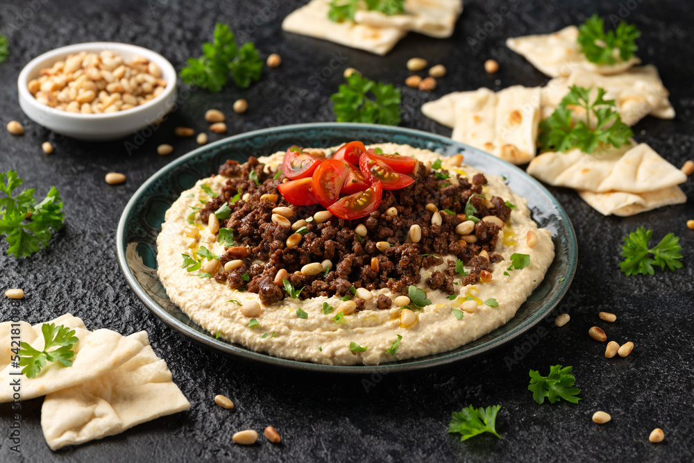 Hummus with spiced ground beef, olive oil, tomatoes and toasted pine nuts