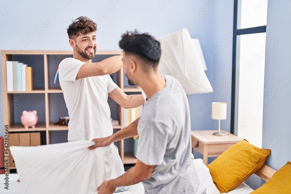 Young couple fighting with pillow on bed at bedrooom Young couple fighting with pillow on bed at bedrooom