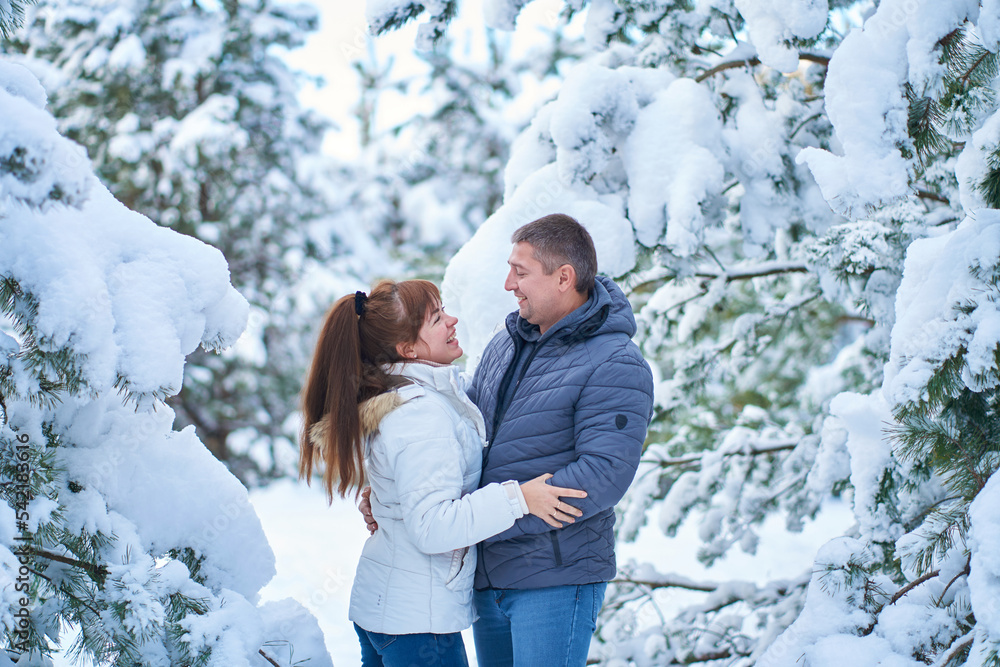 A joyful couple in love walking in winter forest heavy covered with snow A joyful couple in love walking in winter forest heavy covered with snow