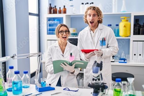 Two people working at scientist laboratory celebrating crazy and amazed for success with open eyes screaming excited.