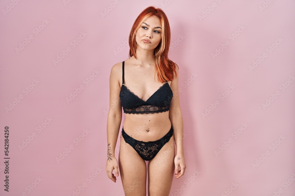 Young caucasian woman wearing lingerie over pink background smiling looking to the side and staring away thinking. Young caucasian woman wearing lingerie over pink background smiling looking to the side and staring away thinking.