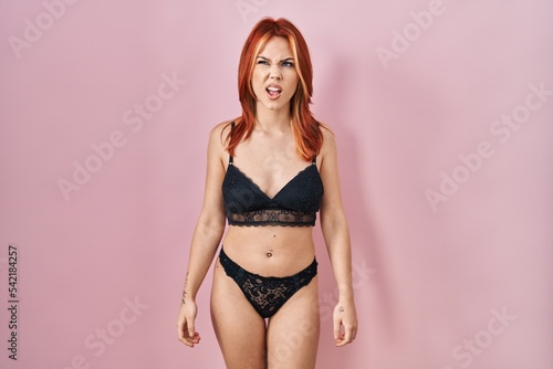 Young caucasian woman wearing lingerie over pink background angry and mad screaming frustrated and furious, shouting with anger. rage and aggressive concept.