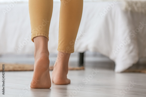 Female bare feet on floor in bedroom, closeup