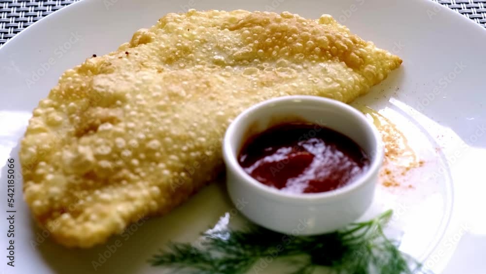 Cheburek is a traditional oriental dish with meat and green onions. Meat dough on a white plate. View from above. Cheburek is a traditional oriental dish with meat and green onions. Meat dough on a white plate. View from above.