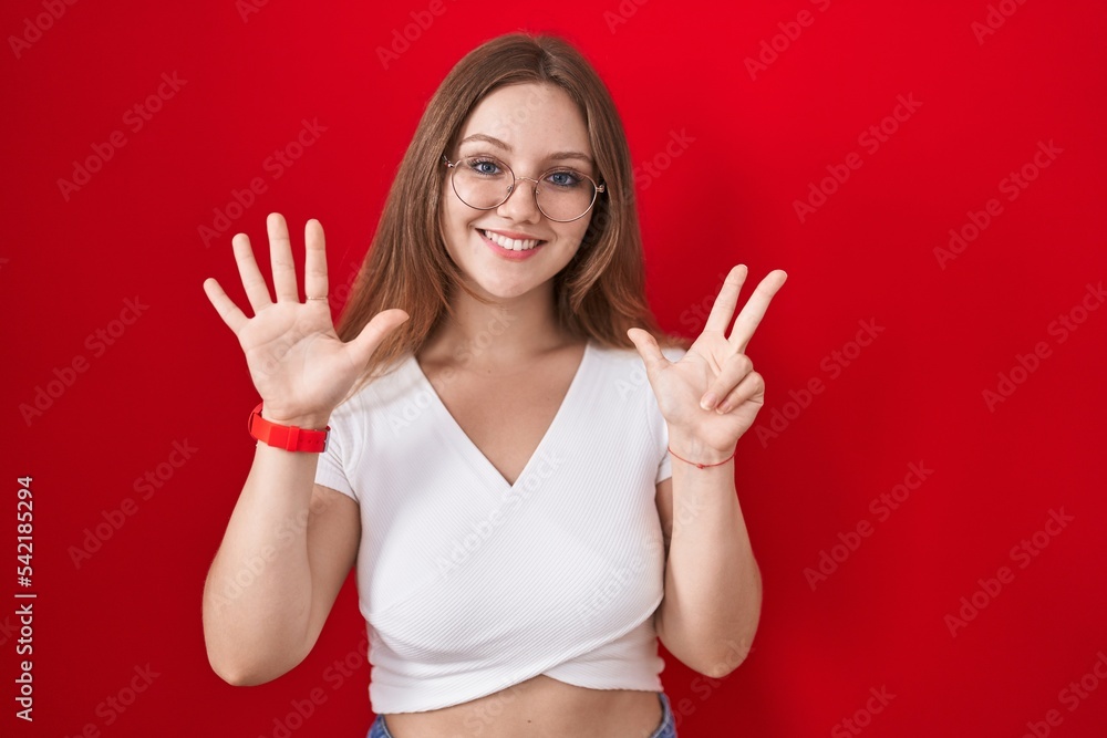 Young caucasian woman standing over red background showing and pointing up with fingers number eight while smiling confident and happy. Young caucasian woman standing over red background showing and pointing up with fingers number eight while smiling confident and happy.