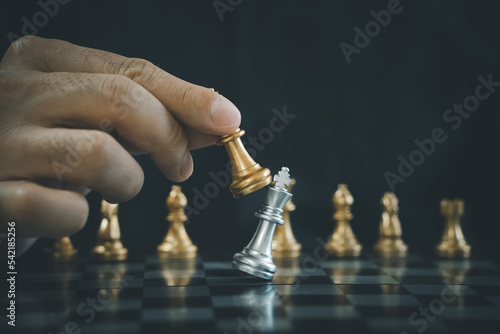 Foto Businessman hand moving gold chess king figure and checkmate opponent during chessboard competition