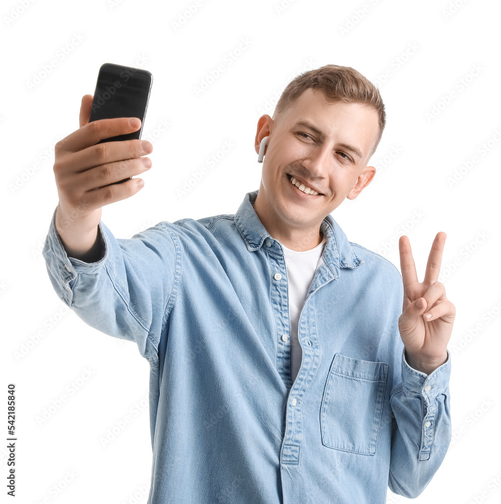 Handsome young man with mobile phone taking selfie on white background Handsome young man with mobile phone taking selfie on white background