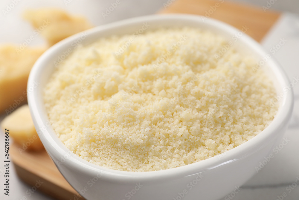 Bowl with grated parmesan cheese on table, closeup Bowl with grated parmesan cheese on table, closeup
