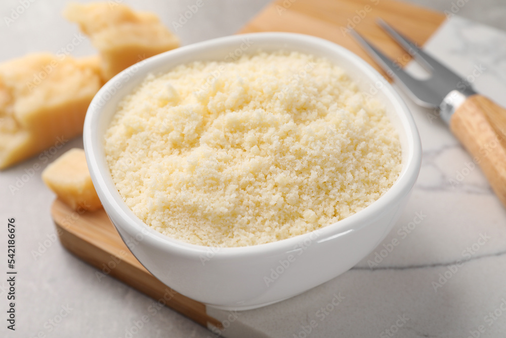 Bowl with grated parmesan cheese on light table, closeup Bowl with grated parmesan cheese on light table, closeup