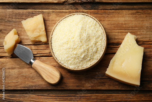 Flat lay composition with grated parmesan cheese and knife on wooden table