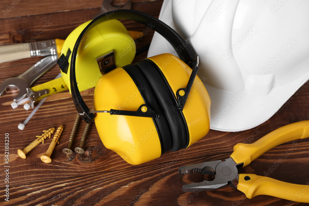 Hearing protectors with builder's tools on dark wooden background, closeup Hearing protectors with builder's tools on dark wooden background, closeup