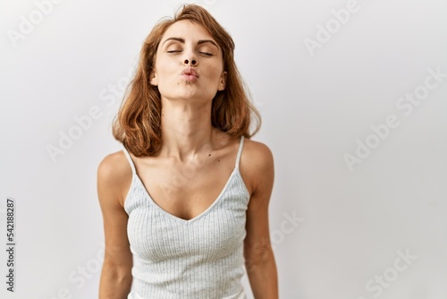 Beautiful caucasian woman standing over isolated background looking at the camera blowing a kiss on air being lovely and sexy. love expression.