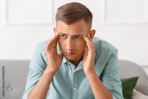Upset young man with nosebl...