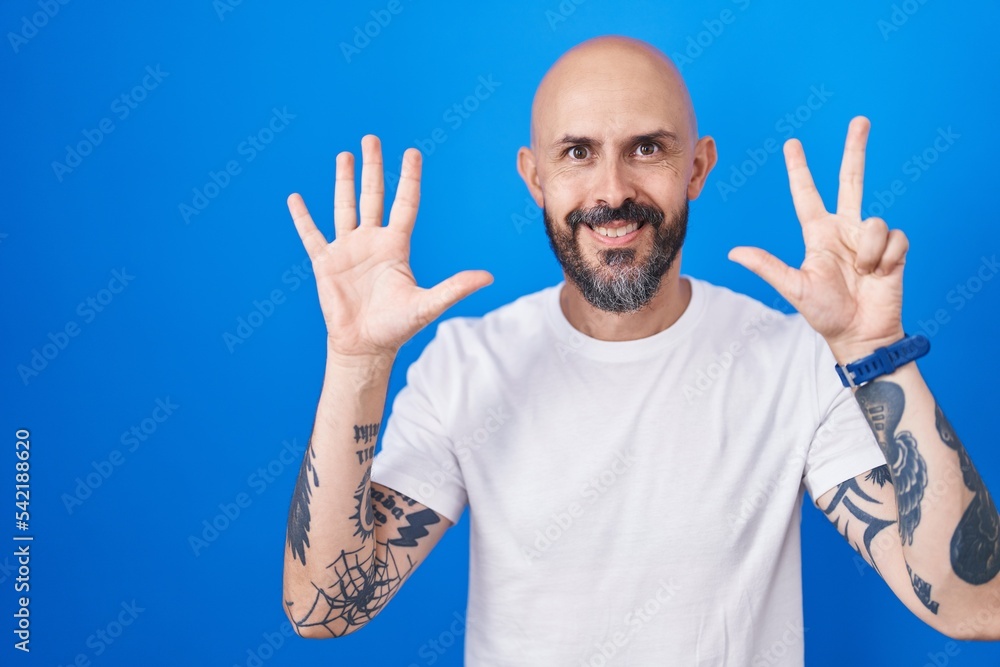 Hispanic man with tattoos standing over blue background showing and pointing up with fingers number eight while smiling confident and happy. Hispanic man with tattoos standing over blue background showing and pointing up with fingers number eight while smiling confident and happy.