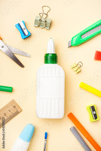 Composition with bottle of glue and different stationery on color background