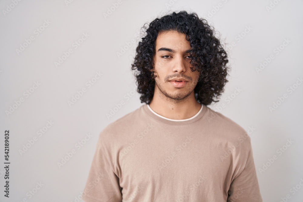 Hispanic man with curly hair standing over white background looking sleepy and tired, exhausted for fatigue and hangover, lazy eyes in the morning. Hispanic man with curly hair standing over white background looking sleepy and tired, exhausted for fatigue and hangover, lazy eyes in the morning.