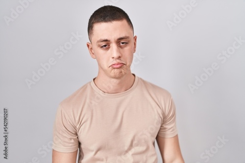 Young man standing over isolated background depressed and worry for distress, crying angry and afraid. sad expression. © Krakenimages.com