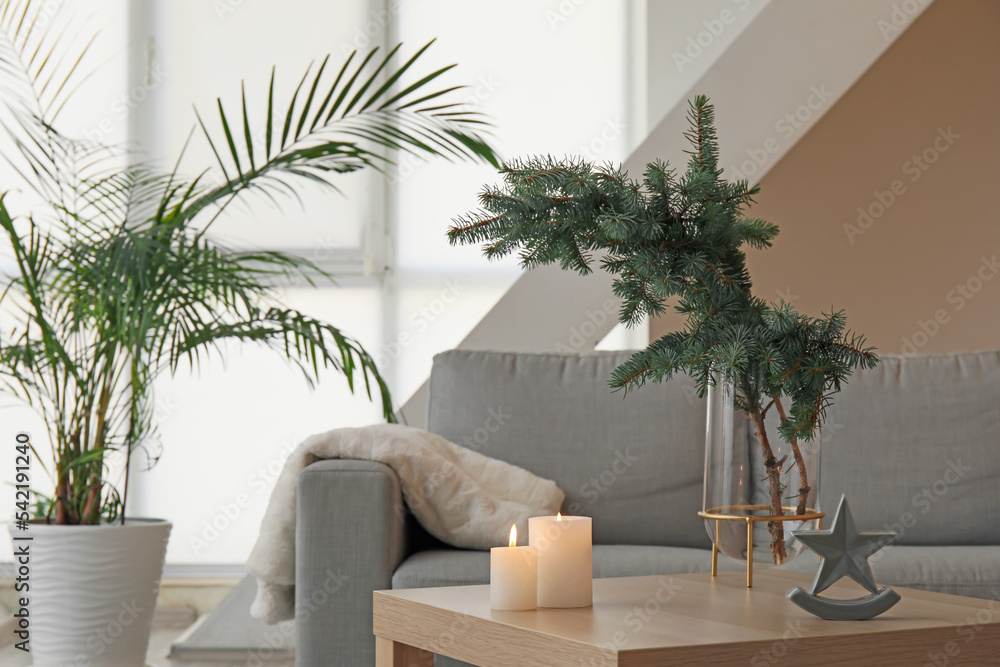 Obraz premium Vase with Christmas branches and candles on table in living room