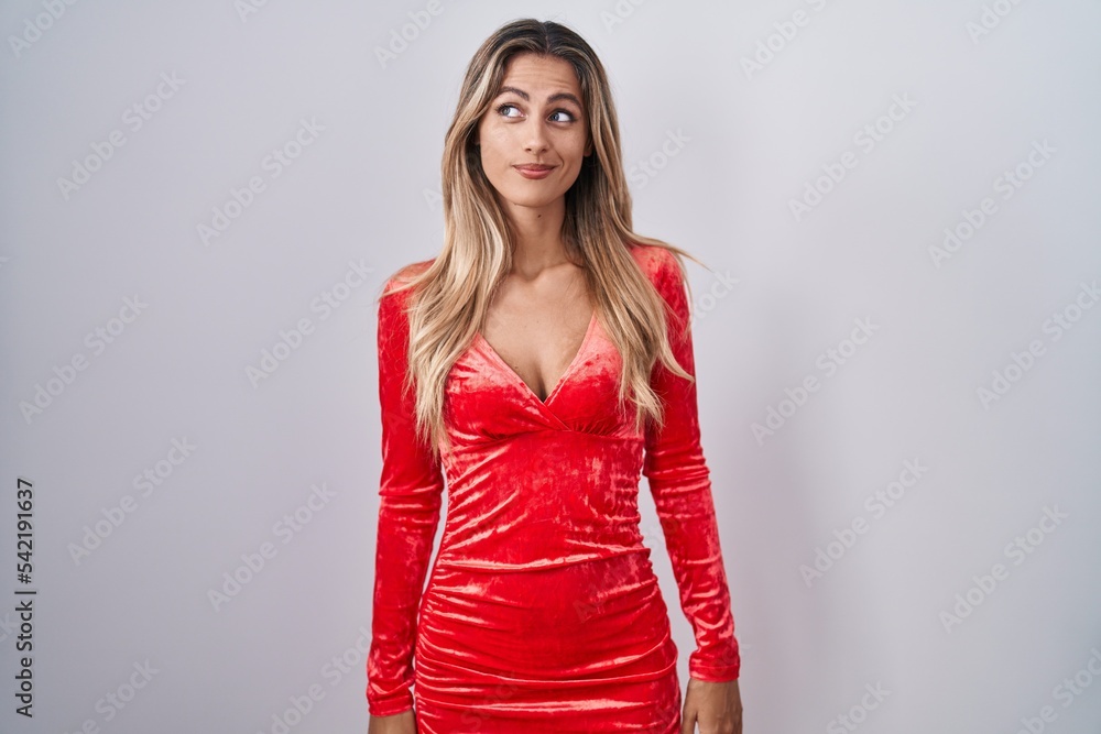 Young blonde woman wearing sexy party dress smiling looking to the side and staring away thinking. Young blonde woman wearing sexy party dress smiling looking to the side and staring away thinking.
