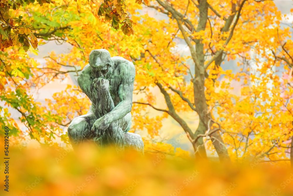 The Thinker sculpture during a colorful autumn day The Thinker sculpture during a colorful autumn day