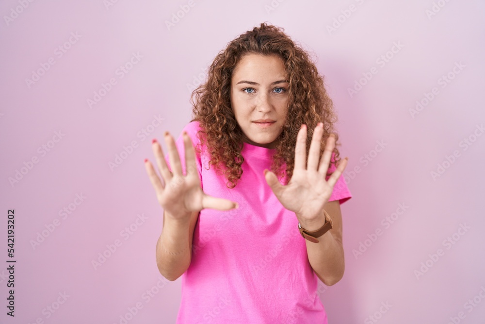 Young caucasian woman standing over pink background afraid and terrified with fear expression stop gesture with hands, shouting in shock. panic concept. Young caucasian woman standing over pink background afraid and terrified with fear expression stop gesture with hands, shouting in shock. panic concept.