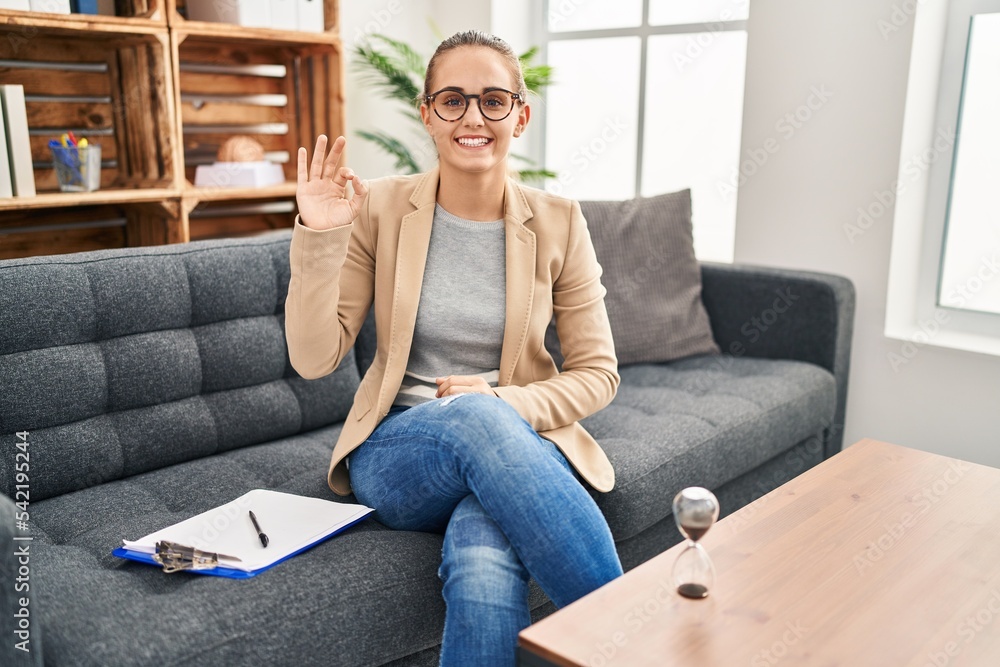 Young woman working at consultation office smiling positive doing ok sign with hand and fingers. successful expression. Young woman working at consultation office smiling positive doing ok sign with hand and fingers. successful expression.
