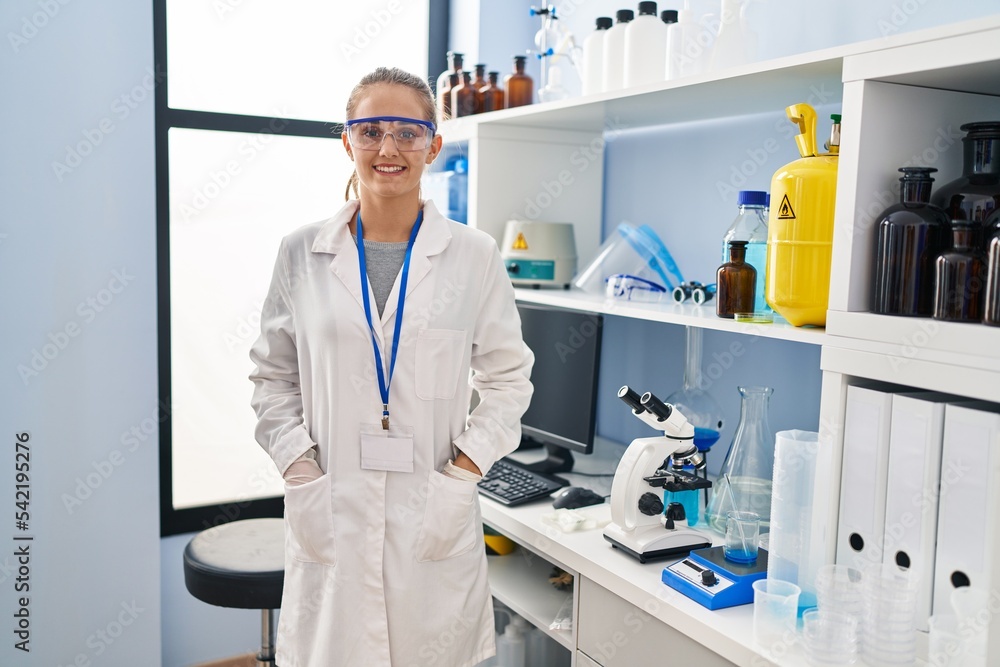 Young blonde woman wearing scientist uniform standing at laboratory