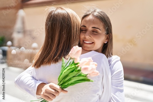 Two women mother and daughter surprise with bouquet of flowers at street