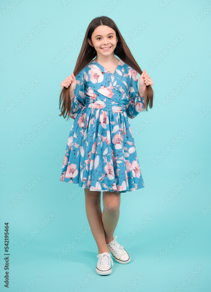 Young graceful teenager child in dress isolated on blue background. Beautiful teen in summer clothing. Happy teenager, positive and smiling emotions. Young graceful teenager child in dress isolated on blue background. Beautiful teen in summer clothing. Happy teenager, positive and smiling emotions.