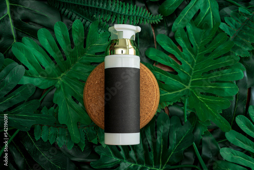 cosmetic product presentation. Cosmetic jar and green leaf on color background. White product bottle, golden cap, black paper product label.