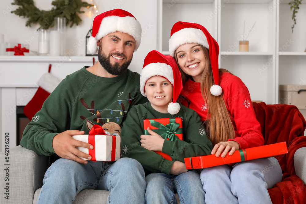 Happy parents with their little son in Santa hats with presents at home on Christmas eve Happy parents with their little son in Santa hats with presents at home on Christmas eve