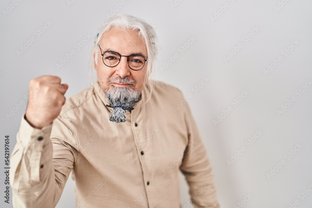 Middle age man with grey hair standing over isolated background angry and mad raising fist frustrated and furious while shouting with anger. rage and aggressive concept. Middle age man with grey hair standing over isolated background angry and mad raising fist frustrated and furious while shouting with anger. rage and aggressive concept.