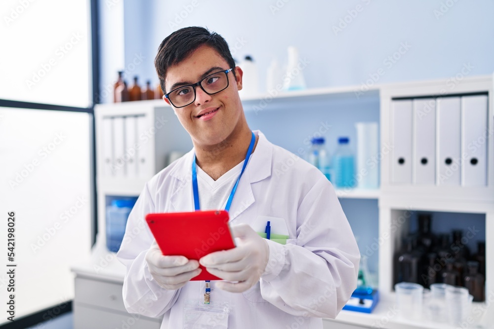 Down syndrome man wearing scientist uniform using touchpad at laboratory Down syndrome man wearing scientist uniform using touchpad at laboratory