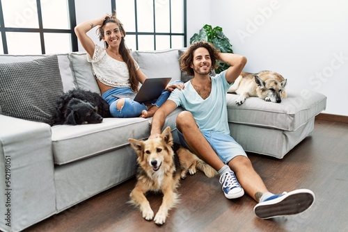 Photography Young hispanic couple with dogs relaxing at home smiling confident touching hair