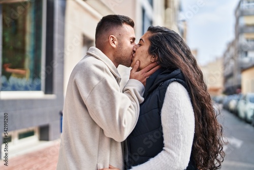 Man and woman couple hugging each other and kissing at street