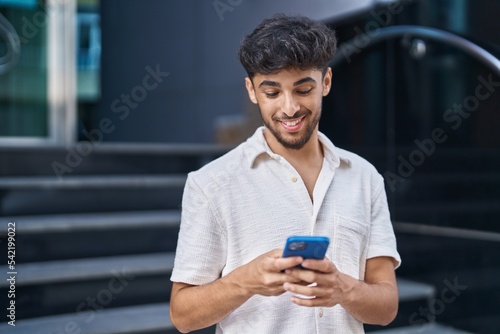Canvas-taulu Young arab man smiling confident using smartphone at street