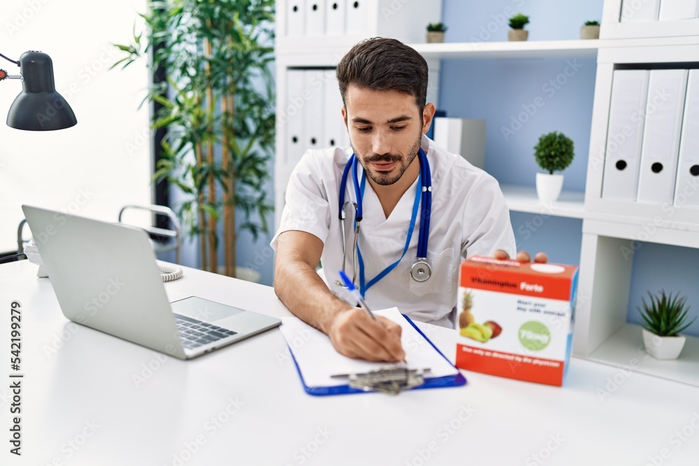 Young hispanic man wearing doctor uniform working at clinic Young hispanic man wearing doctor uniform working at clinic