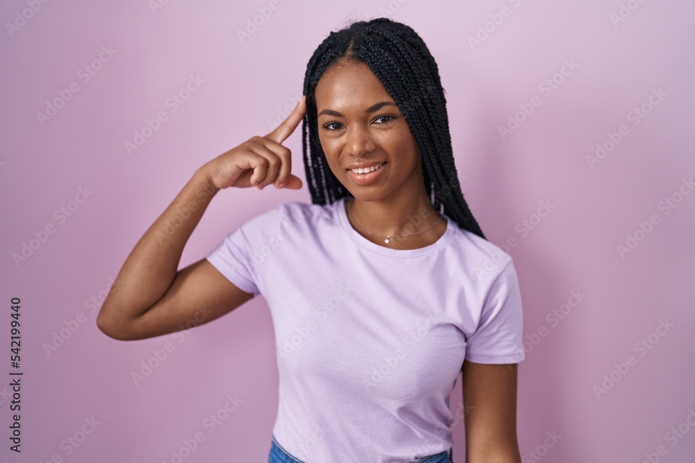 African american woman with braids standing over pink background smiling pointing to head with one finger, great idea or thought, good memory African american woman with braids standing over pink background smiling pointing to head with one finger, great idea or thought, good memory