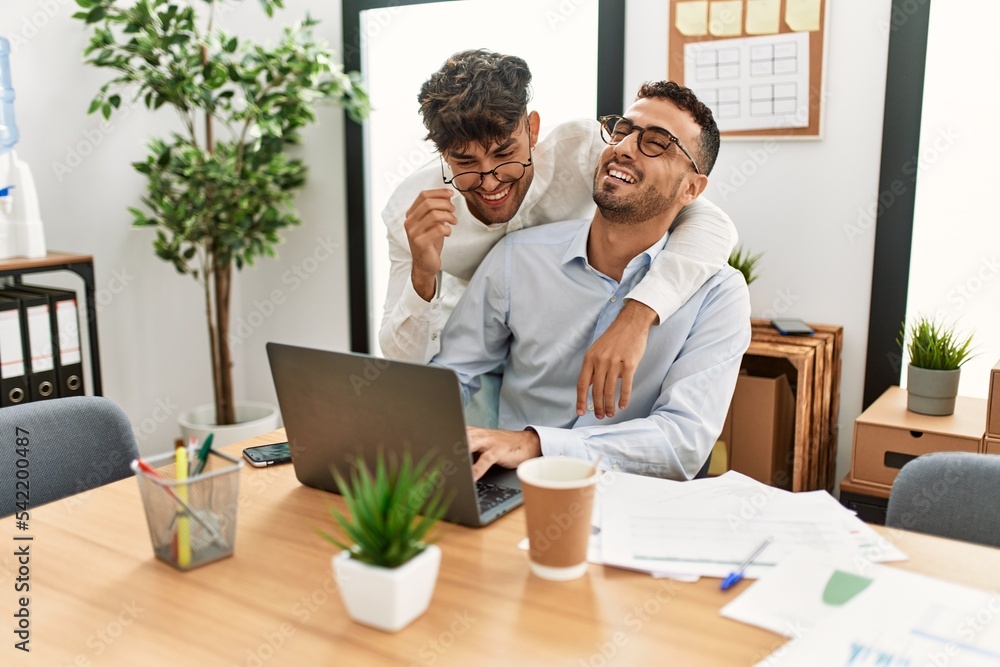 Two hispanic men couple hugging each other working at office Two hispanic men couple hugging each other working at office