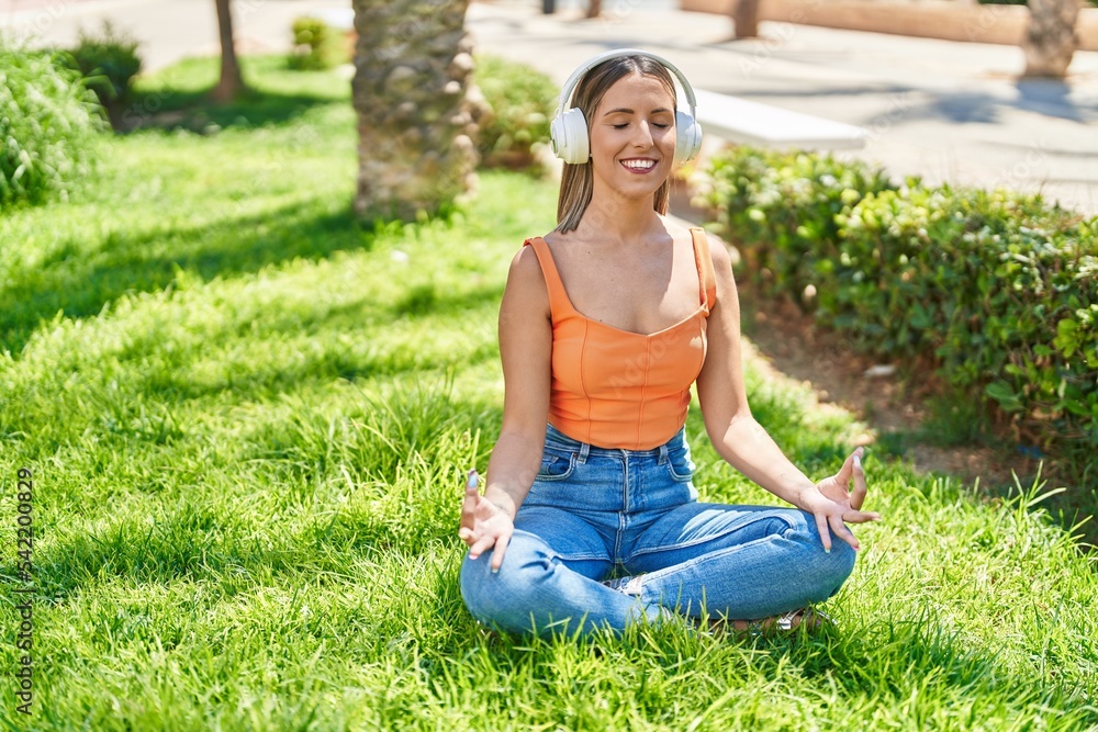 Young beautiful hispanic woman doing yoga exercise using headphones at park Young beautiful hispanic woman doing yoga exercise using headphones at park