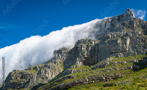 View of clouds rolling over Table Mountain from below with the cable building visible above